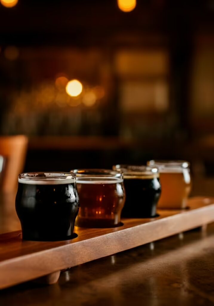 25 Best Gift Ideas for Dads Who Have Everything 4 A close-up of a craft beer flight with four different types of beer on a wooden paddle.